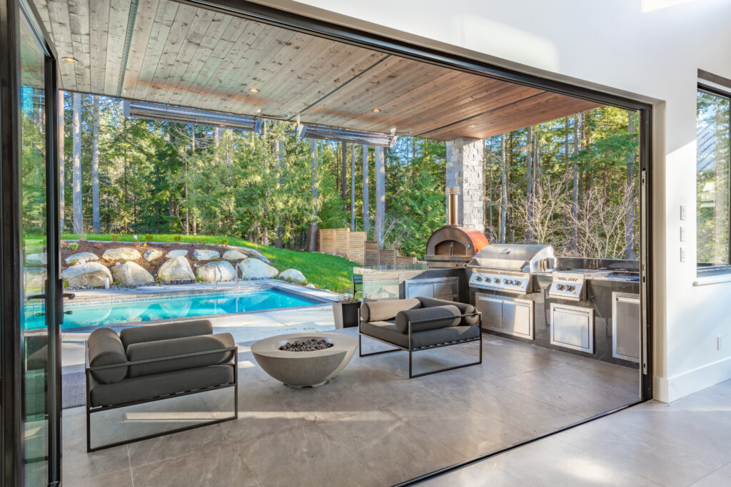 Outdoor kitchen luxury brought to life with a stone patio, grill, and nearby pool.