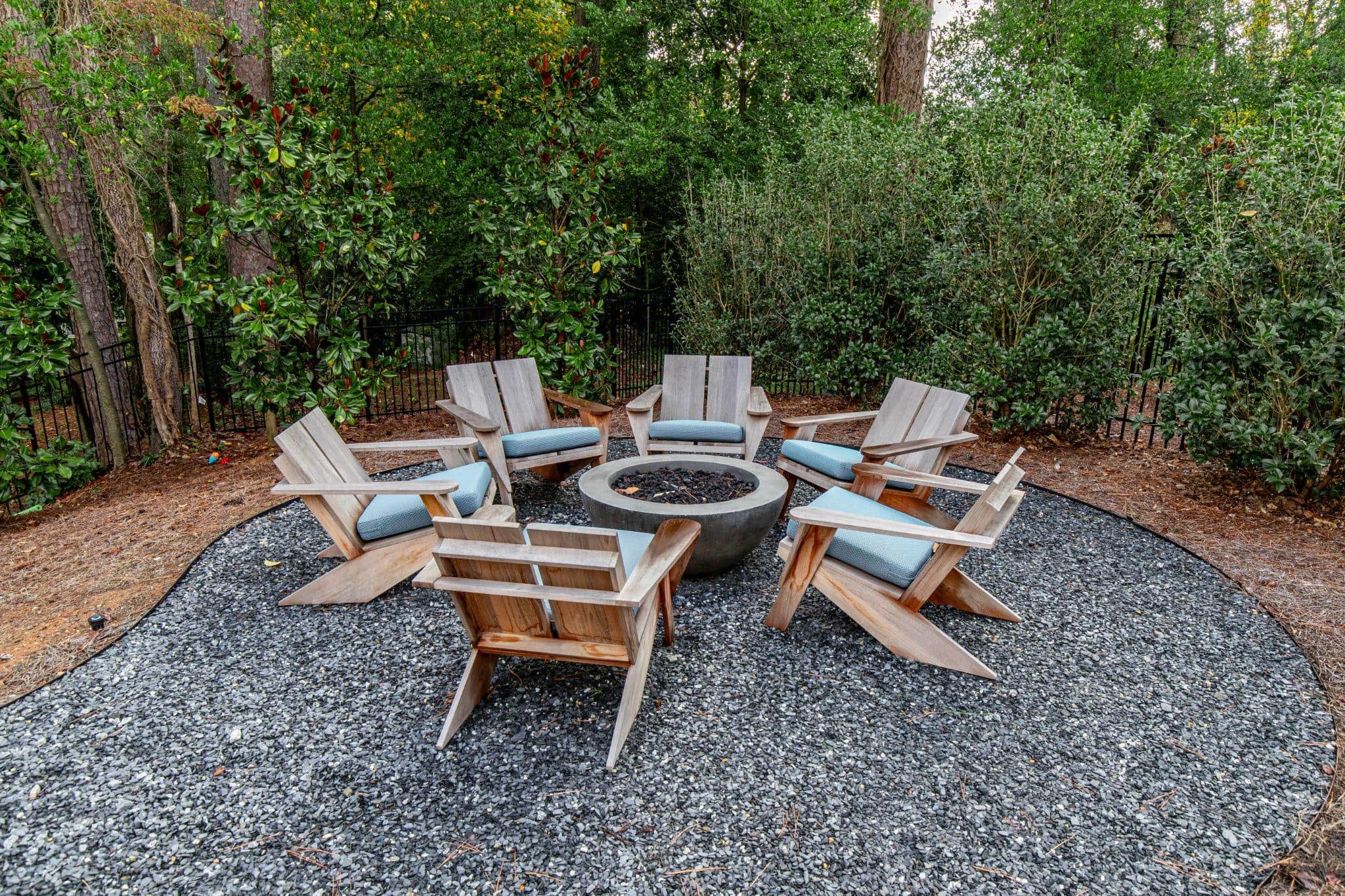 Circular gravel fire pit patio with wooden Adirondack chairs