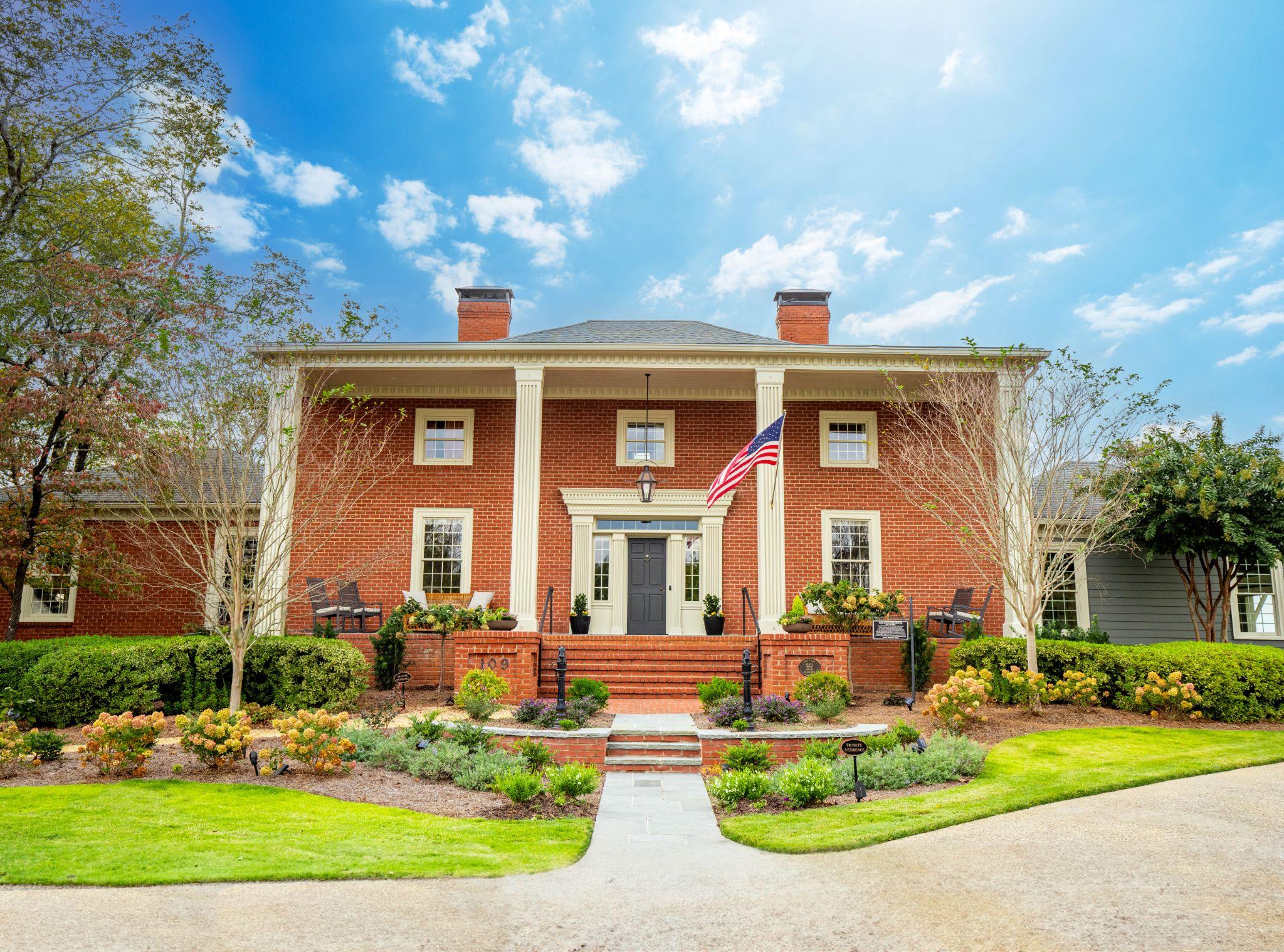 Classic red brick estate with columned front porch and manicured landscaping