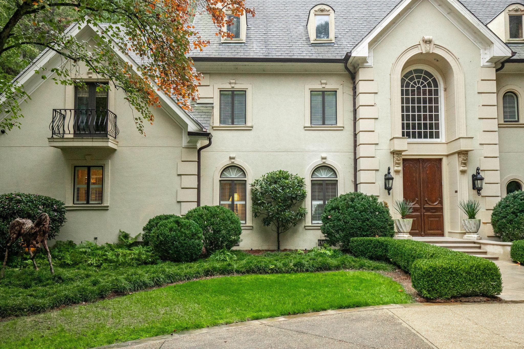 Elegant front entry with manicured hedges, green lawn, and classic architectural details