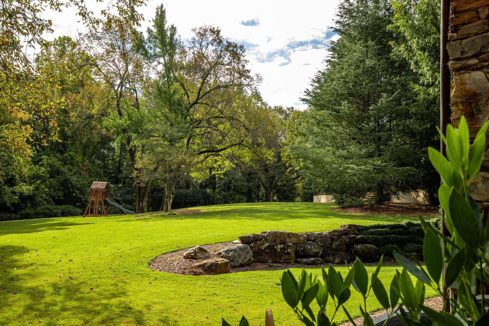Expansive green backyard lawn with natural stone outcropping.