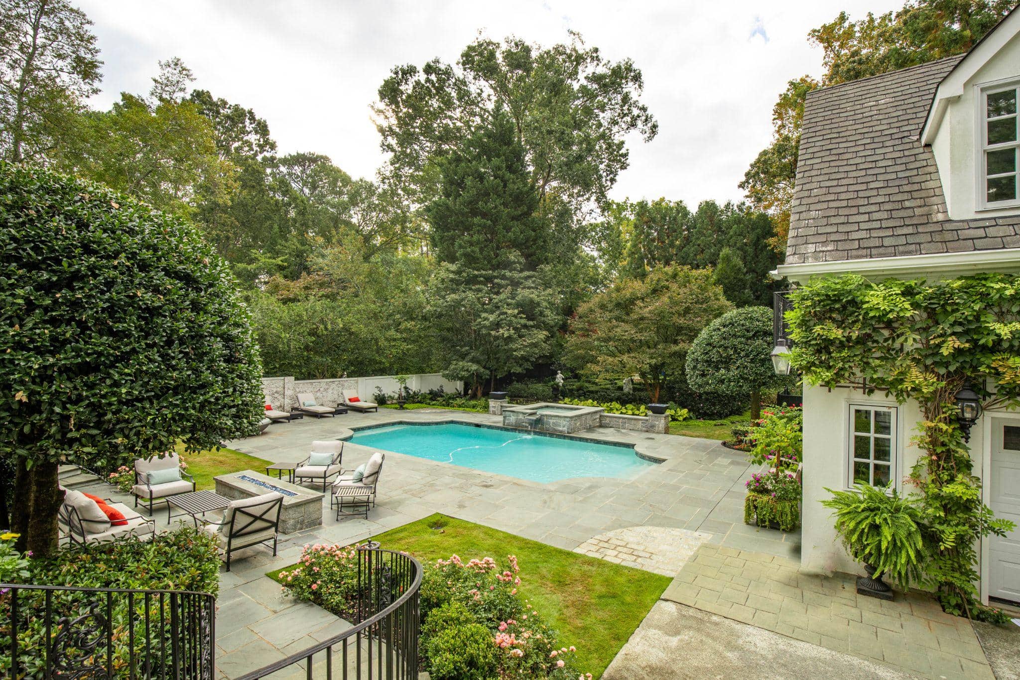 Formal backyard pool with stone patio and garden seating
