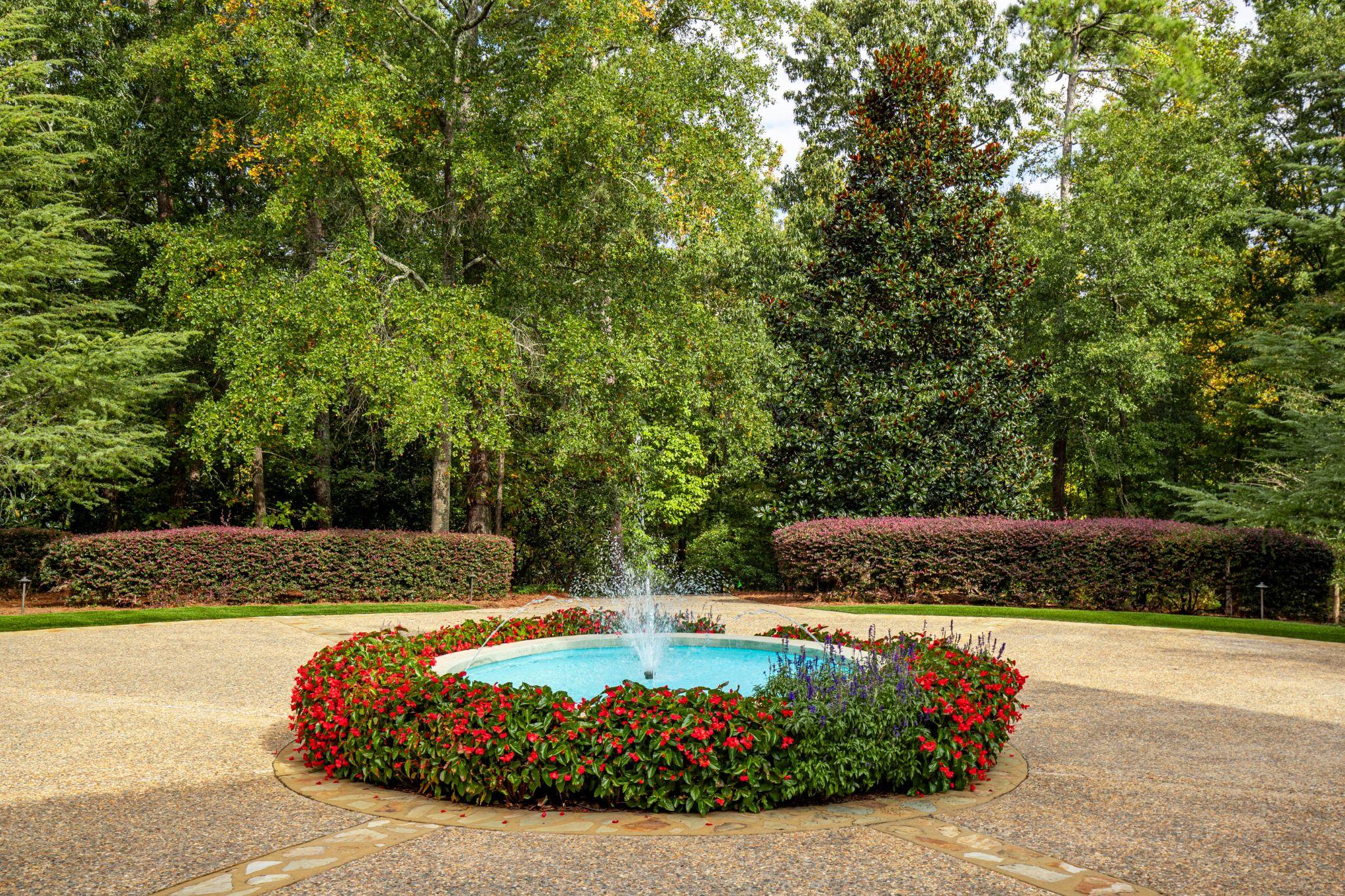 Formal garden fountain surrounded by red seasonal flowers