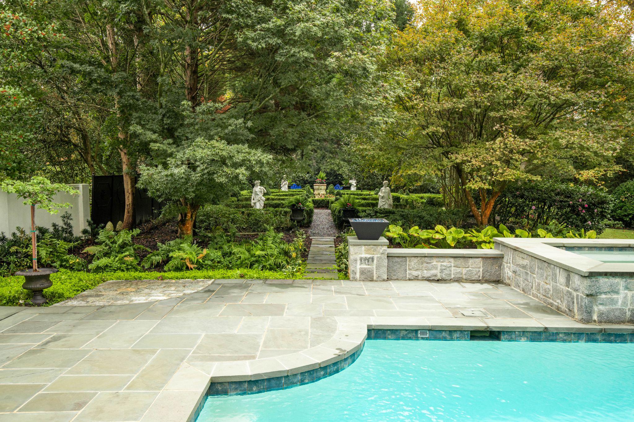 Formal garden terrace overlooking pool with stone walls and symmetrical layout