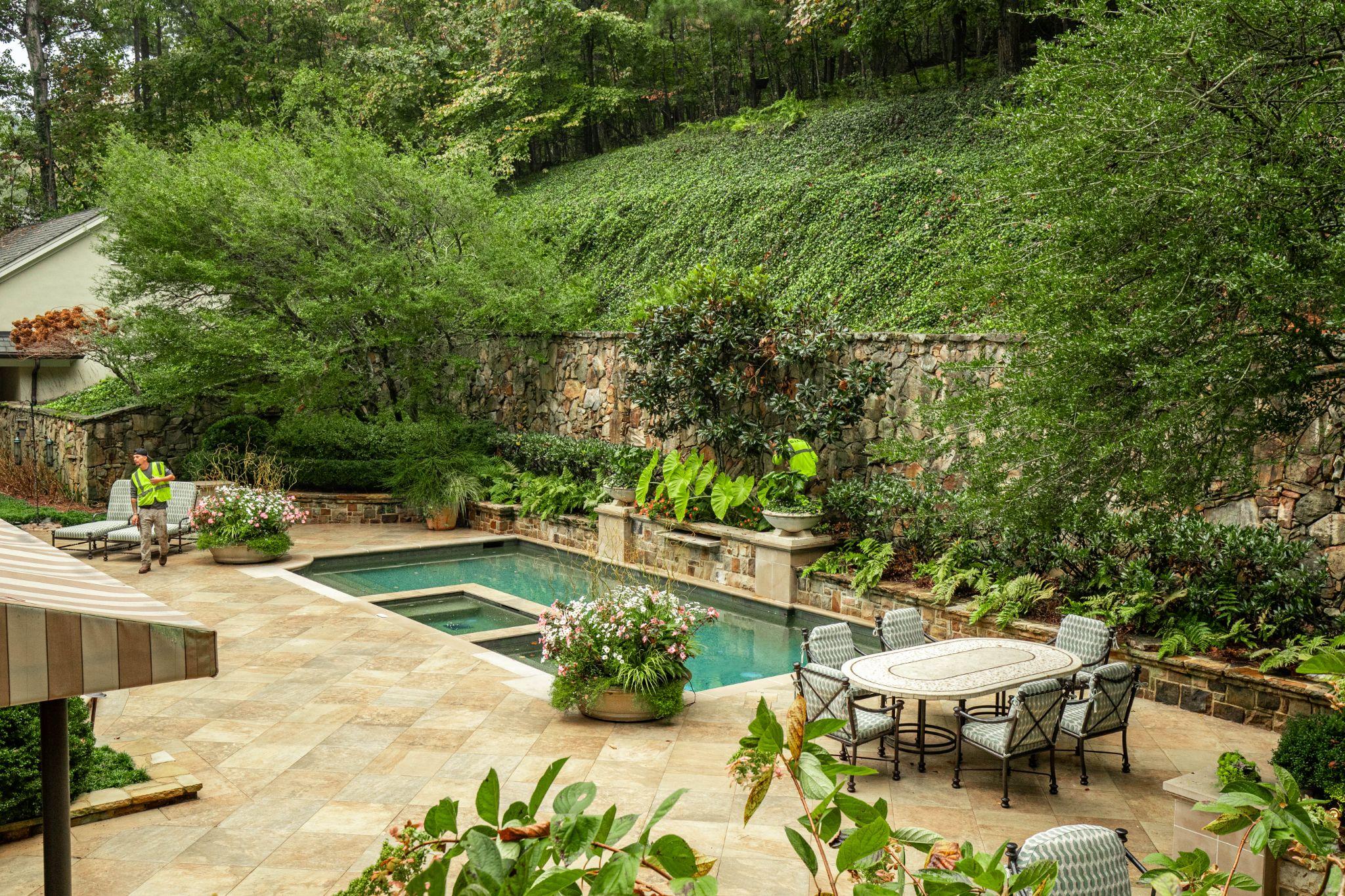 Luxury pool and spa with stone retaining wall and lush plantings
