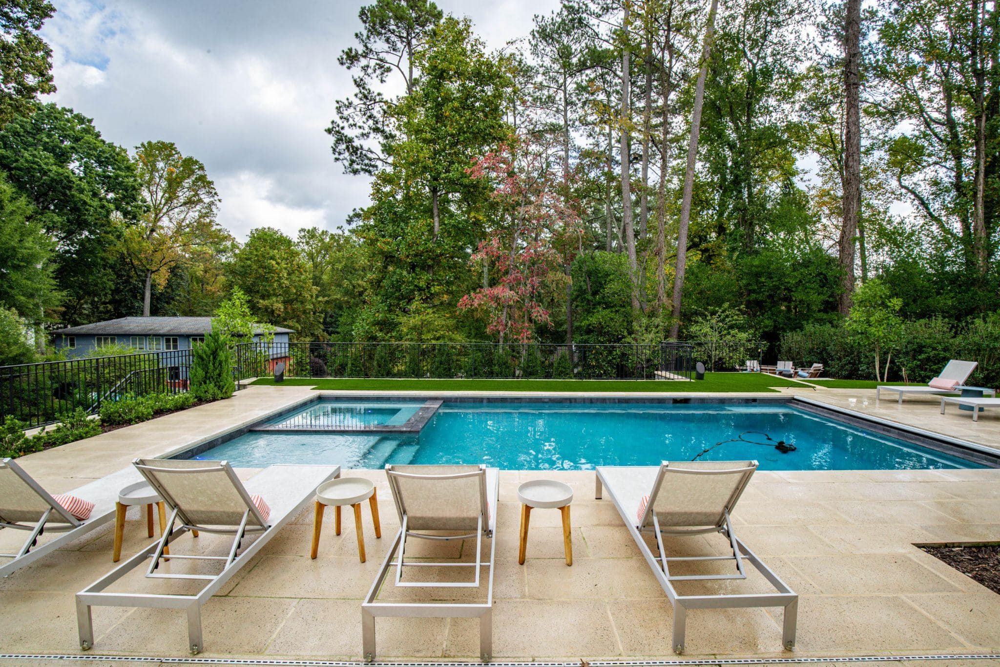 Modern rectangular pool with sun loungers and fenced lawn
