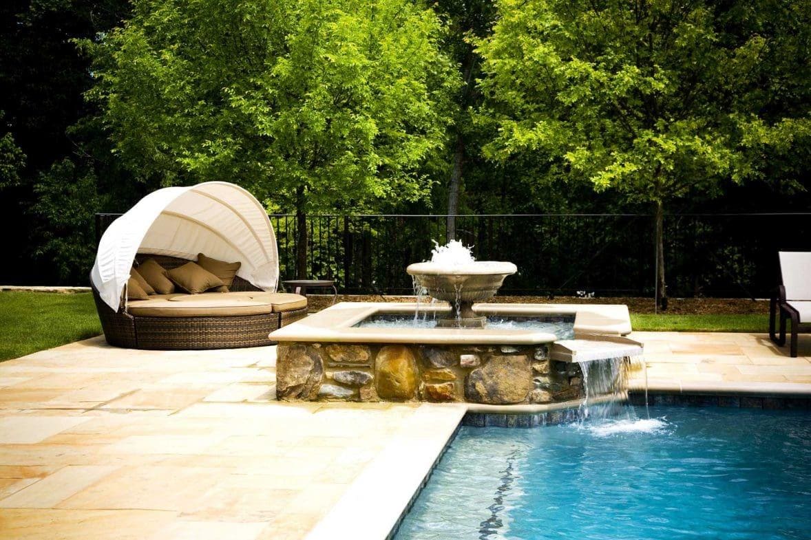 Poolside spa with cascading water feature and cabana daybed