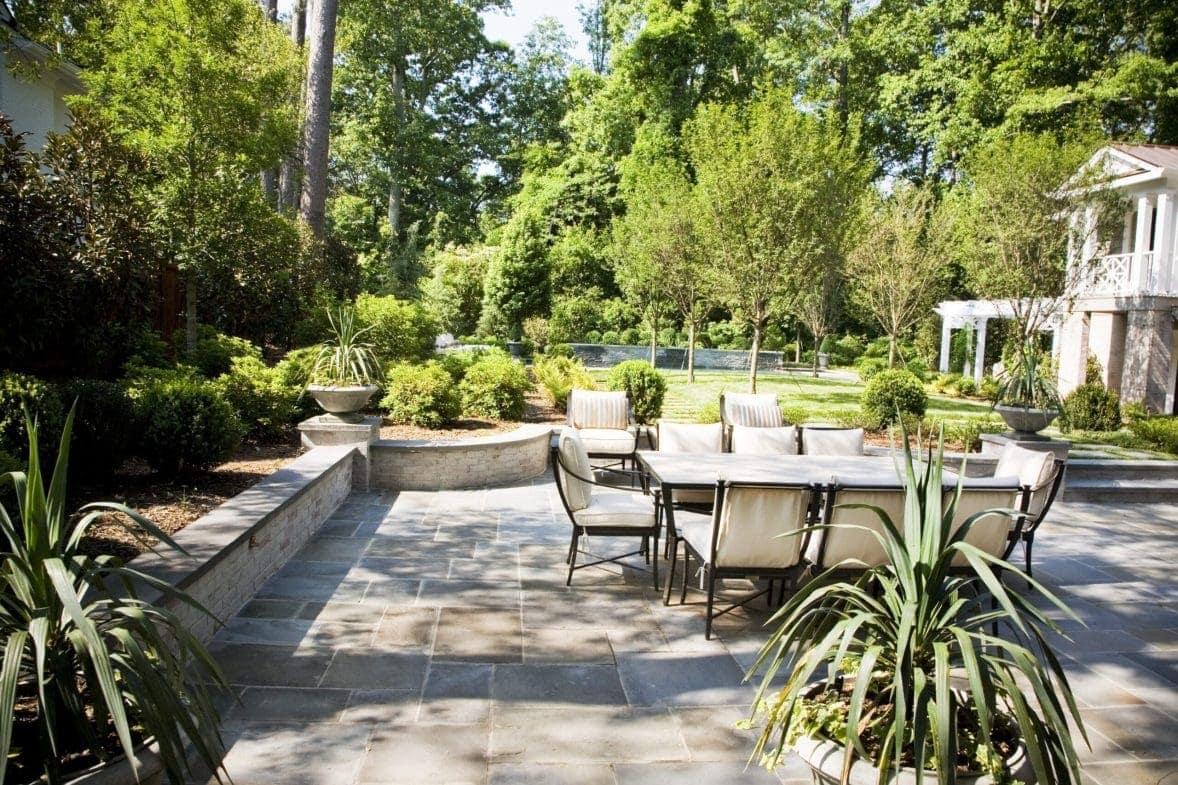 Spacious backyard patio with dining area, raised planters, and manicured lawn