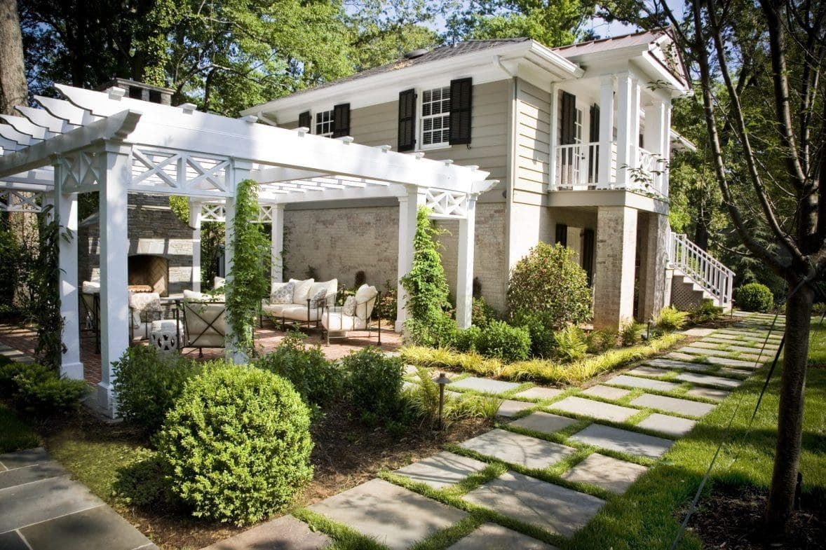 White pergola patio with outdoor fireplace and structured planting beds